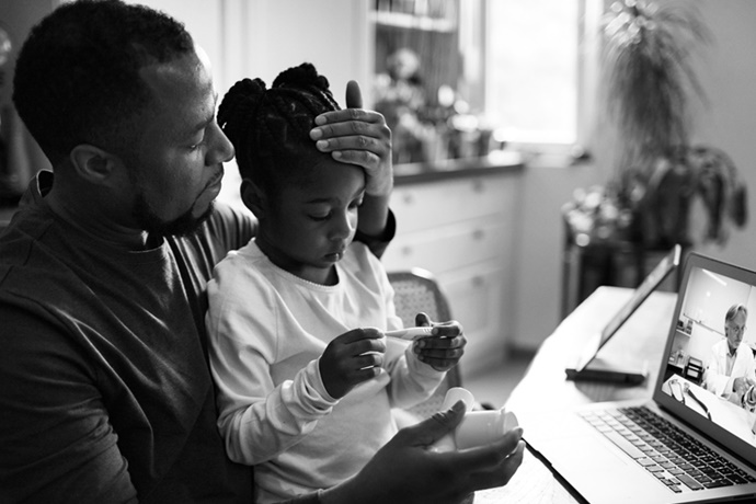 Father and Sick Child Virtual Visit with Doctor on Laptop